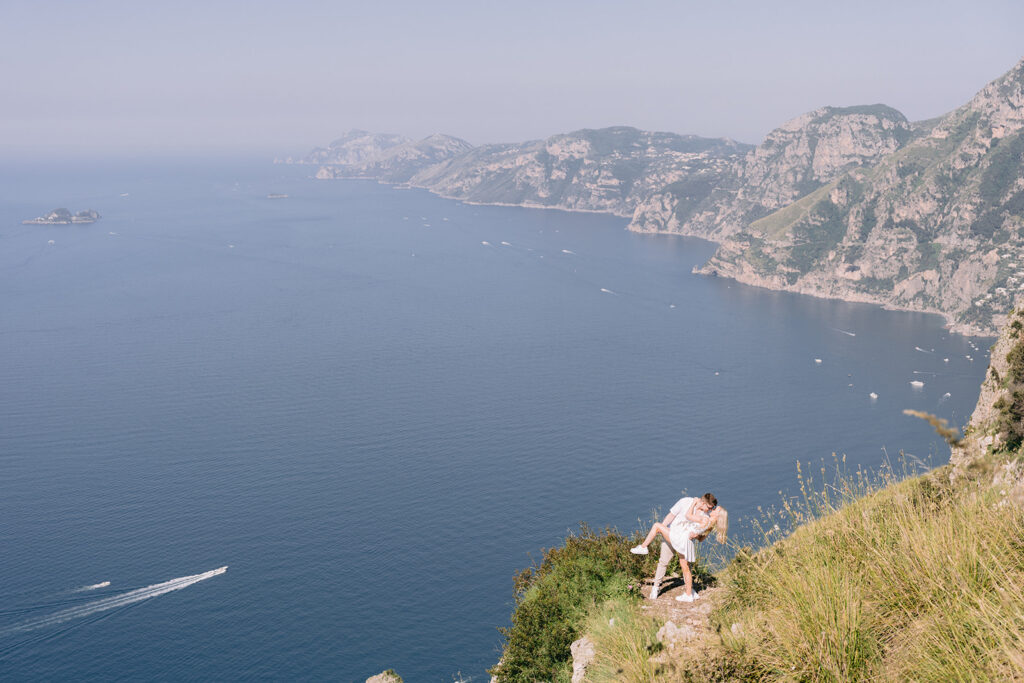 the couple kissing with a beautiful landscape backdrop of amalfi coast