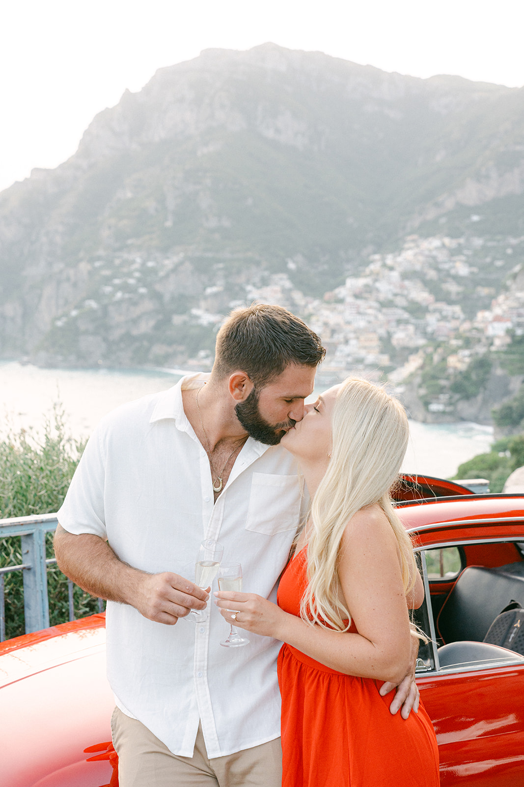 happy couple kissing with a vintage car in amalfi coast