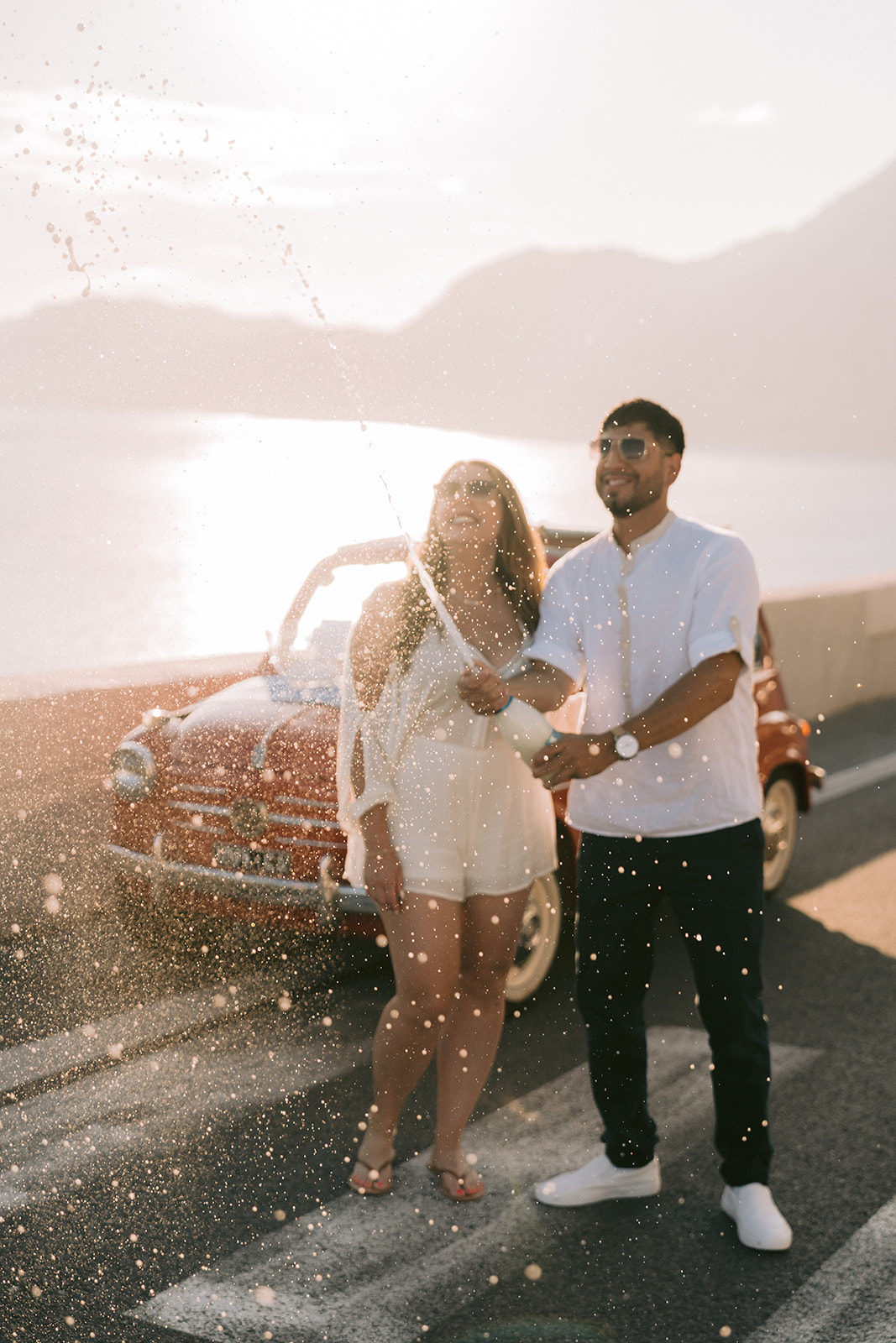 the happy couple opening a champagne bottle in positano