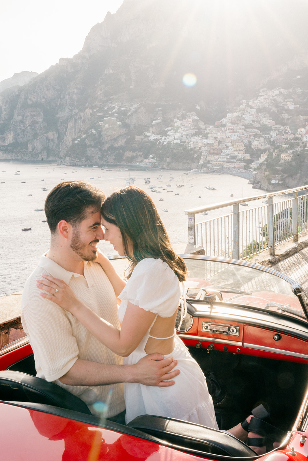happy couple in a red vintage italian car for their engagement photoshoot