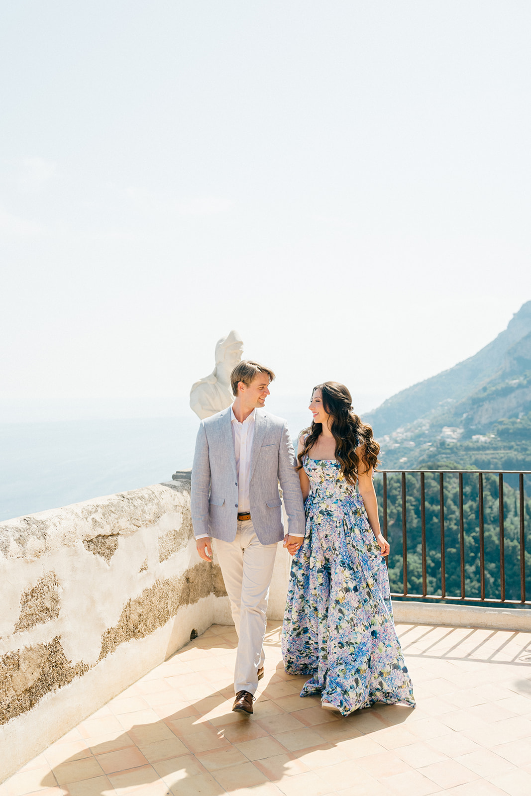a man wearing a causal blue suit while the lady wearing a blue floral pattern dress