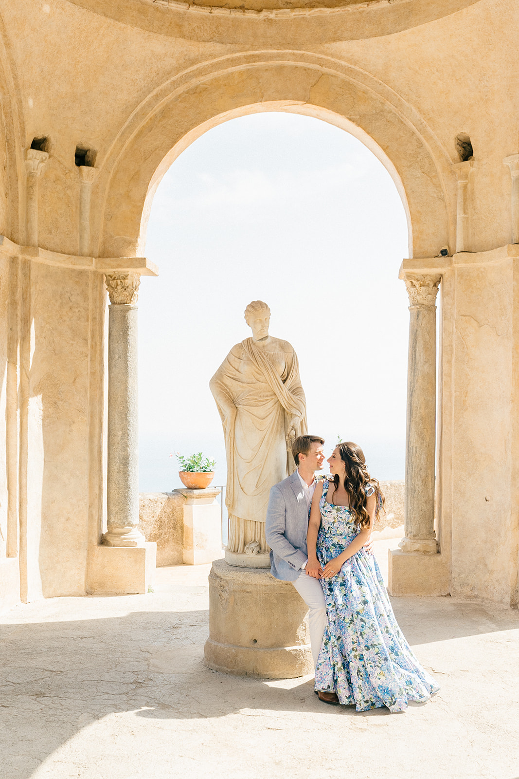 couple sitting next to a statue in Villa Cimbrone