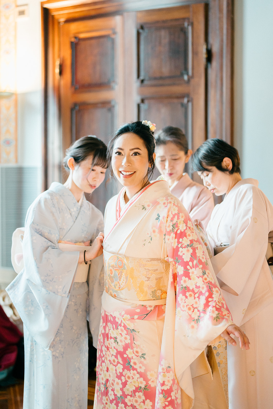 bride getting ready as 3 ladies help her put on her Japanese wedding attire