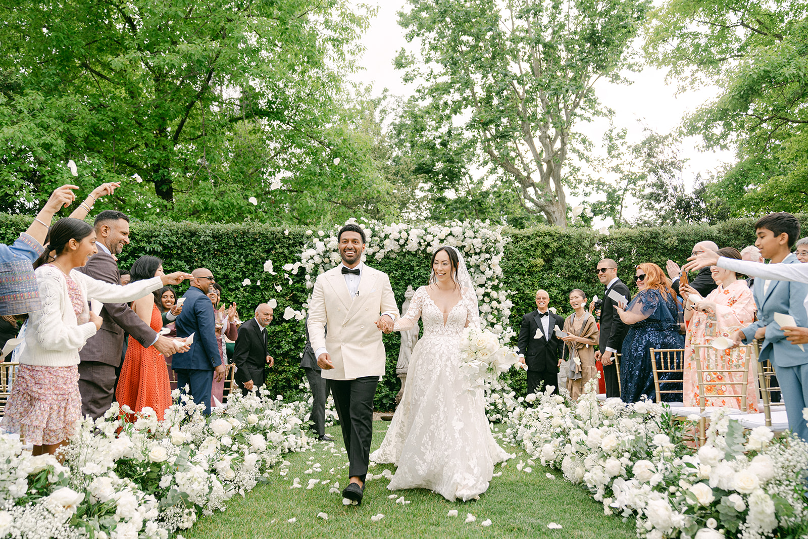 documentary wedding photo during a classic wedding ceremony outdoors in Tuscany as guests throws rose petals