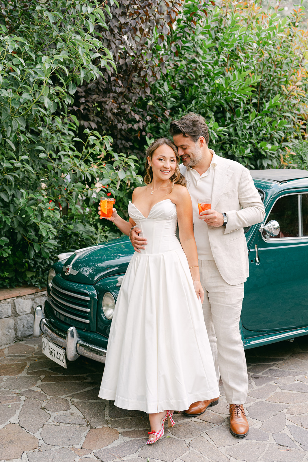 outdoor wedding photo of the bride and groom with their aperol spritz