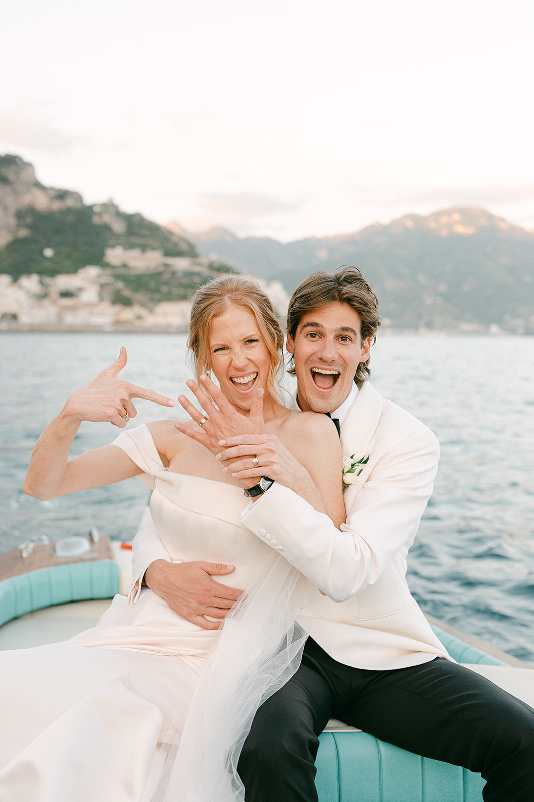 Andrea Gallucci - Destination Wedding Photographer- Amalfi Coast Positano Santorini Barcellona Rome Ravello Paris New York Newly married couple standing on a yacht along the Amalfi Coast, capturing elegant wedding portraits with Mediterranean blue waters and dramatic cliffs.