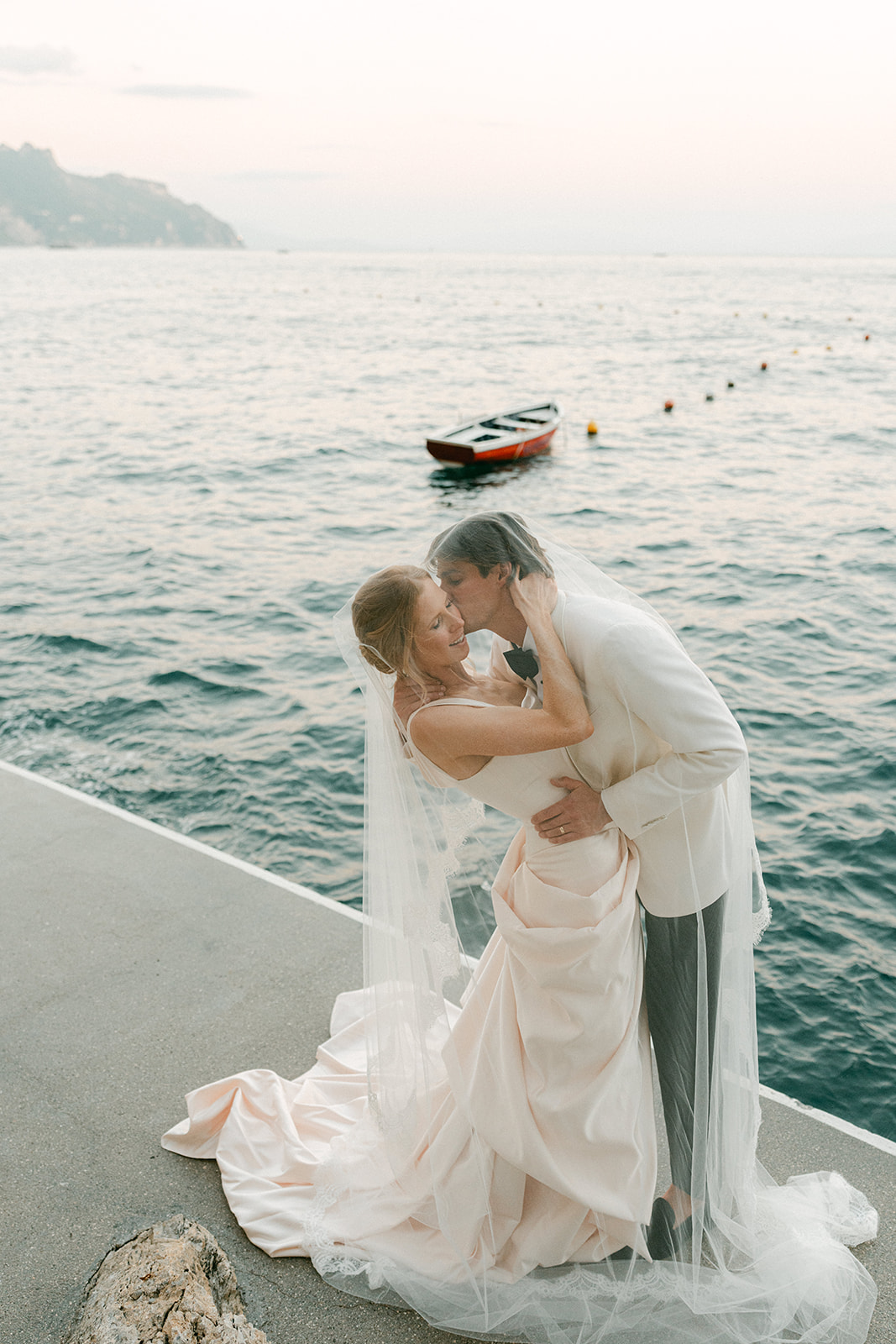 Andrea Gallucci - Destination Wedding Photographer- Amalfi Coast Positano Santorini Barcellona Rome Ravello Paris New York Elegant bride and groom posing on a luxury yacht in Italy after their Amalfi Coast wedding, surrounded by sparkling sea and cinematic coastal views.